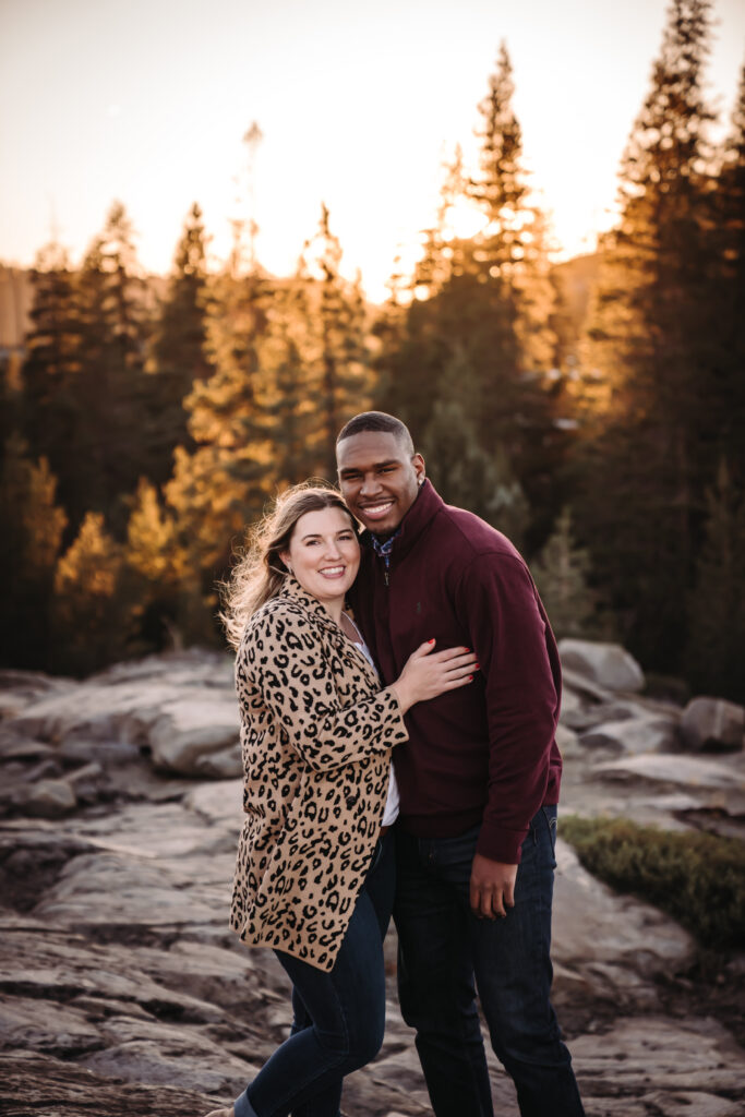 a couple smiling with trees and mountains in the backdrop