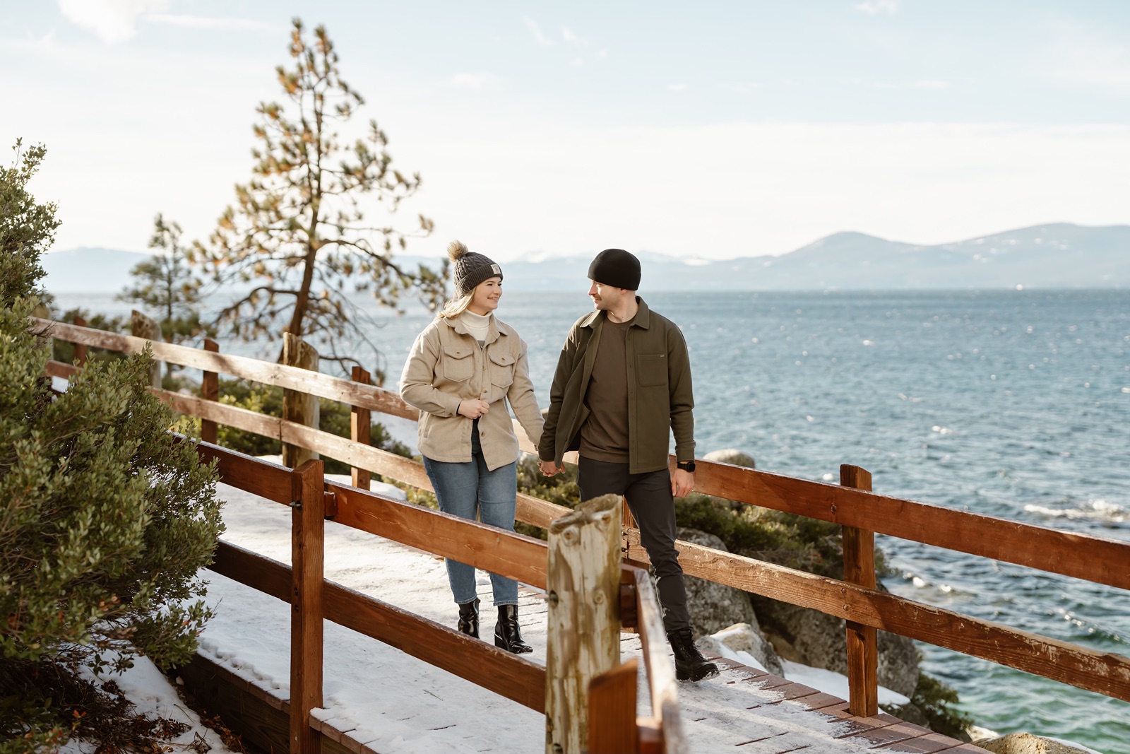 Man and woman walking across bridge with Lake Tahoe mountain backdrop