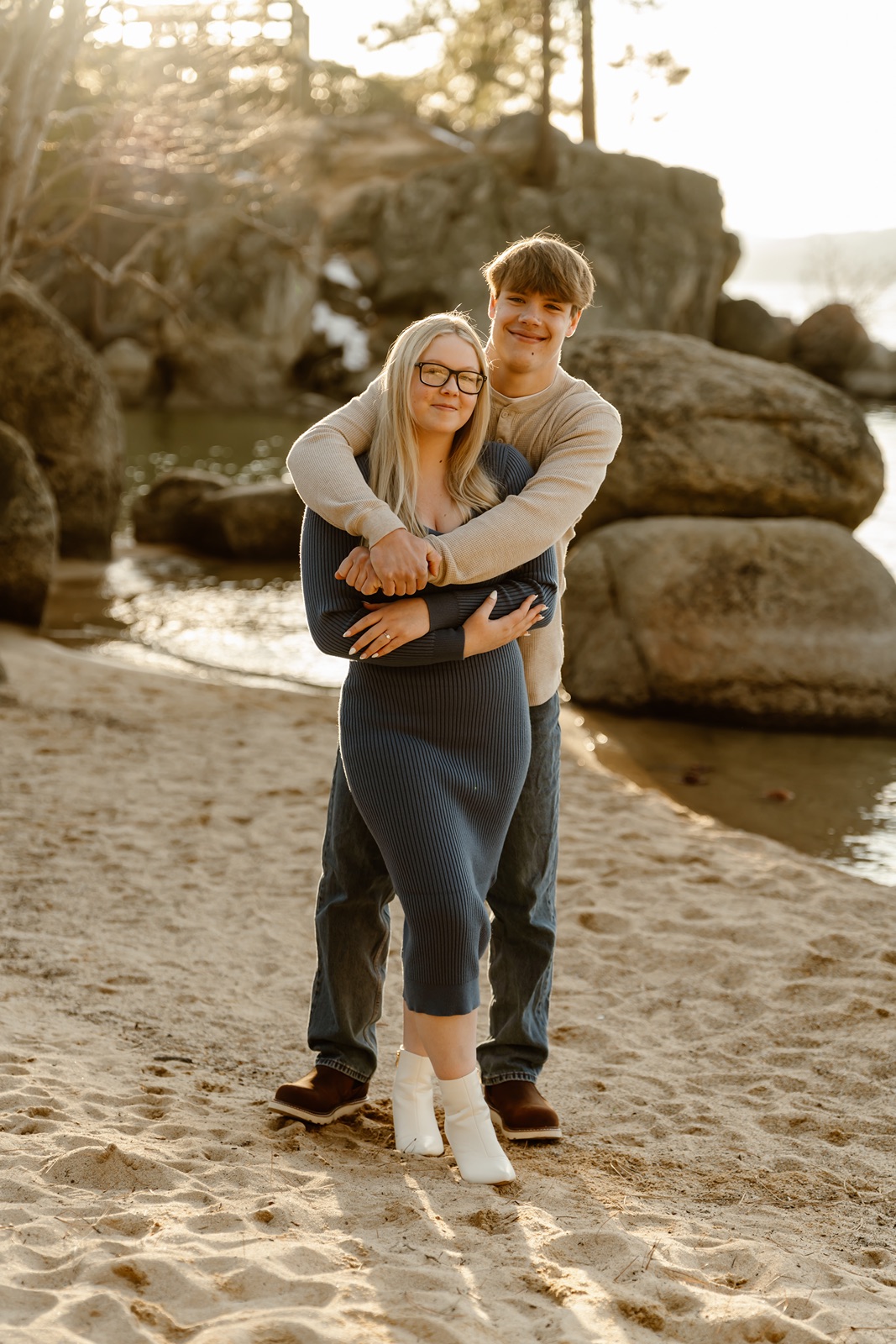 Man hugs woman from behind as they smile for Lake Tahoe engagement photos