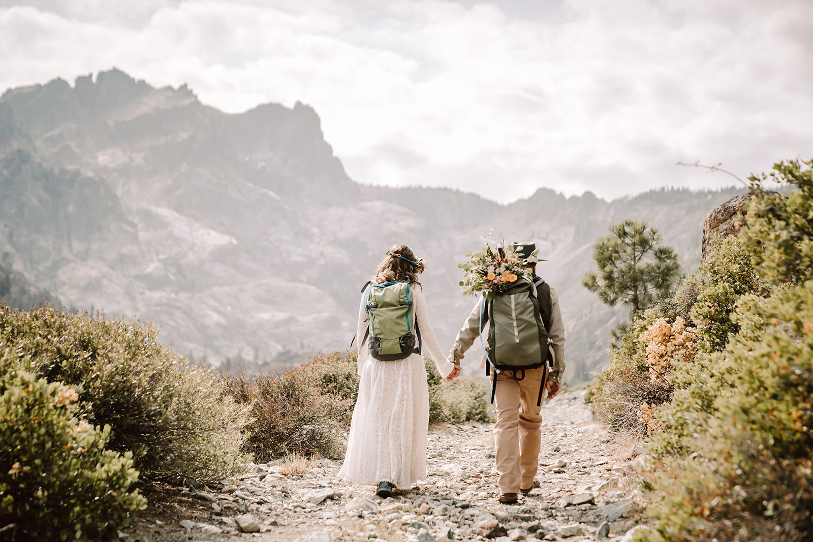 an elopement couple wearing backpacks and hiking next to the Sierra Buttes