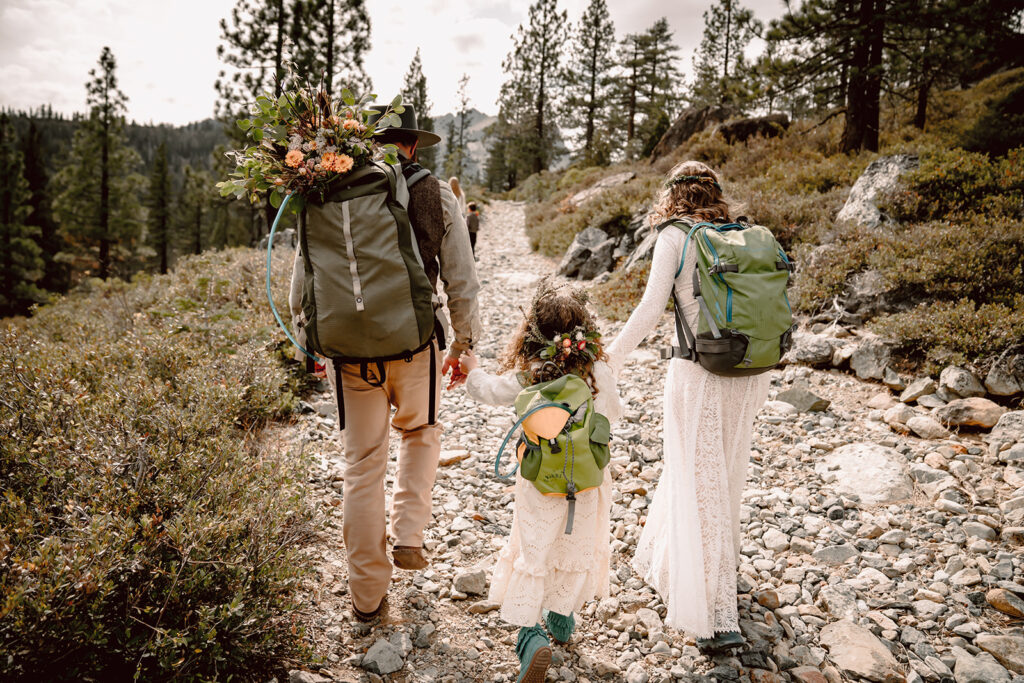 A bride and groom hiking with their daughter on their adventure elopement in Northern California