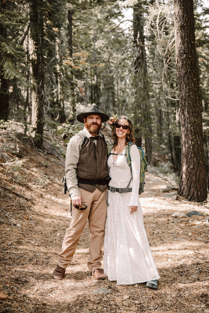 a bride and groom standing on the trail in the forest on their elopement day