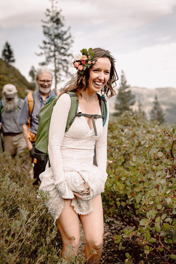a bride holding up her dress while she is hiking on her elopement day