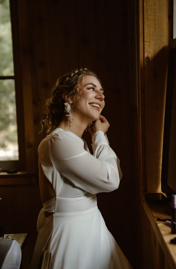 a bride getting ready at her airbnb standing in front of a mirror