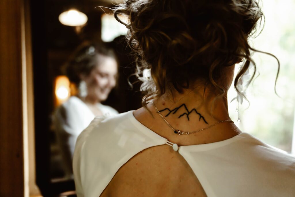 a mountain tattoo on the back of a bride neck