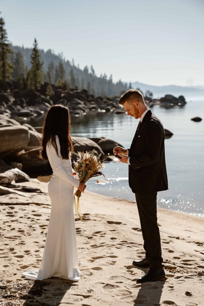 A bride and groom reading vows to each other on a beach in Lake Tahoe