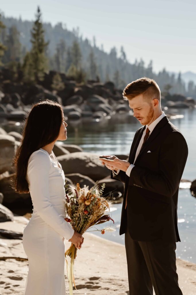 a bride and groom reading vows to each other on a beach in Lake Tahoe