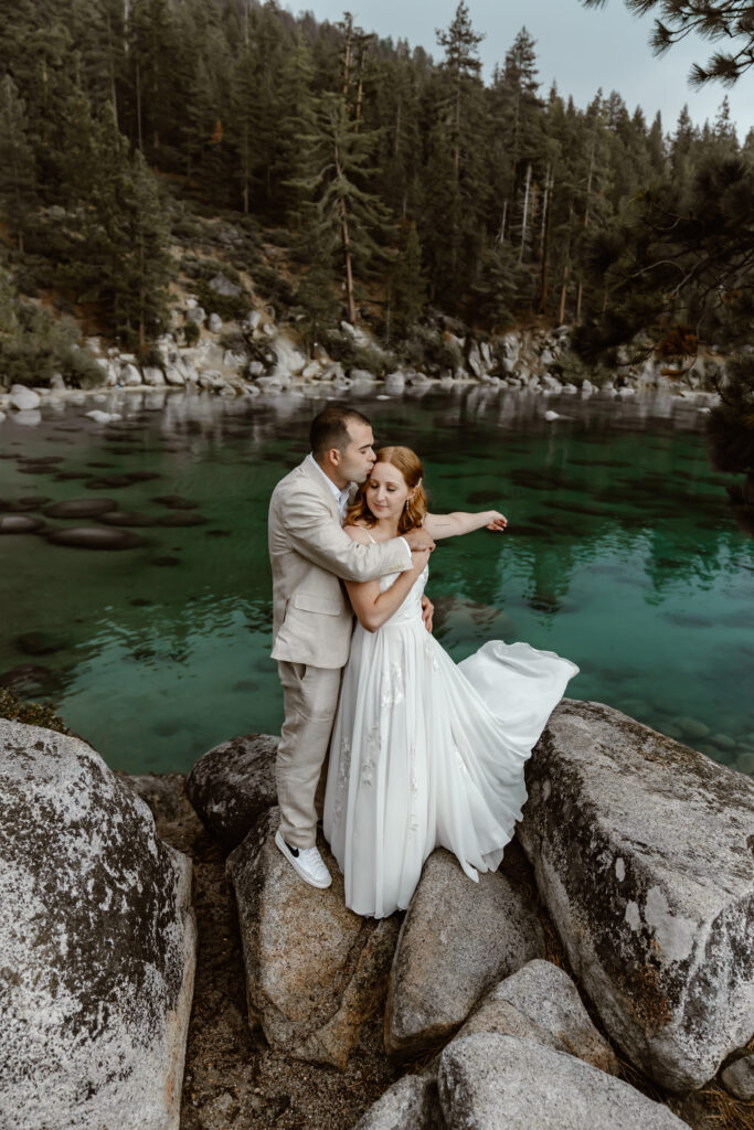 An elopement couple standing on a rock overlooking Secret Cove for their elopement in Lake Tahoe