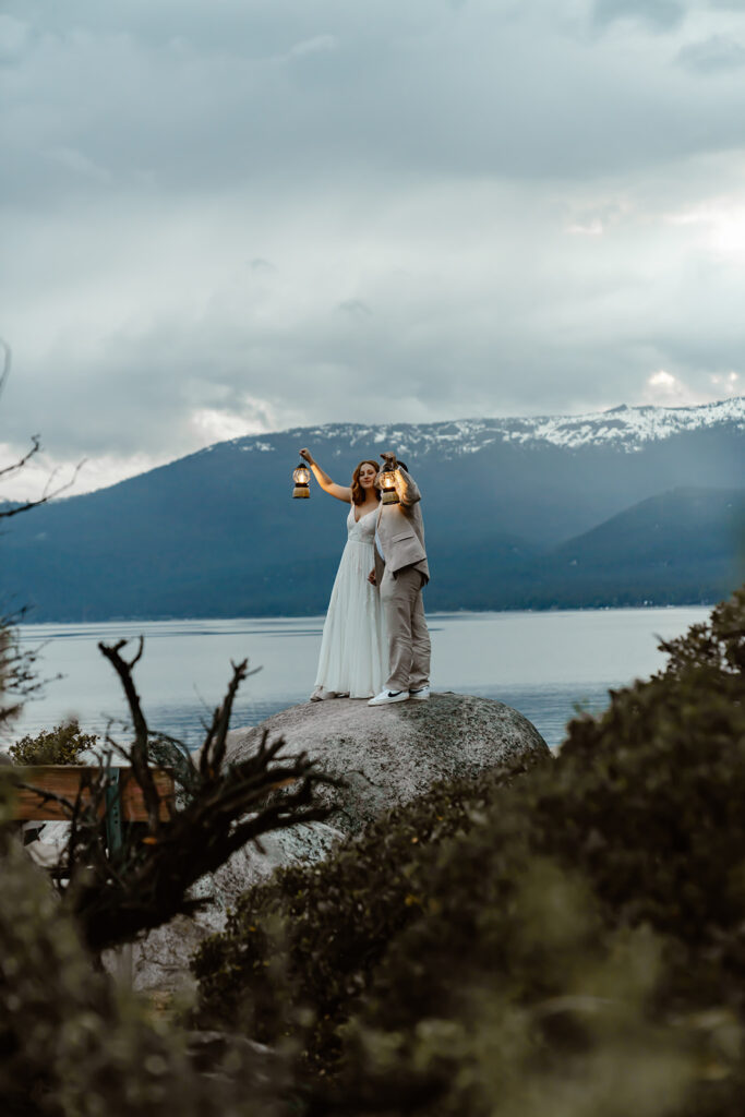  a couple holding some lanters and standing on a boulder for their elopement day in 
Lake Tahoe