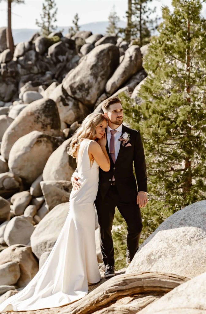 A wedding couple standing on some boulders with the sun on their back for their elopement in Lake Tahoe