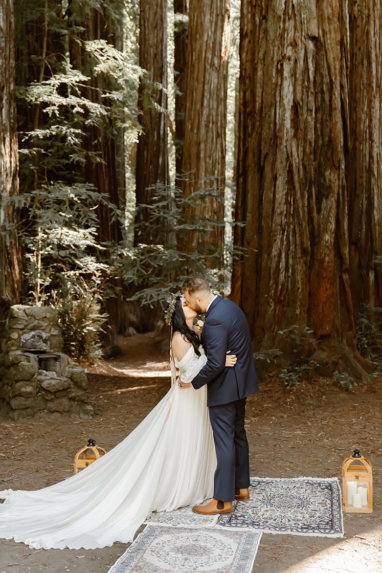 Bride and groom kiss at their forest elopement