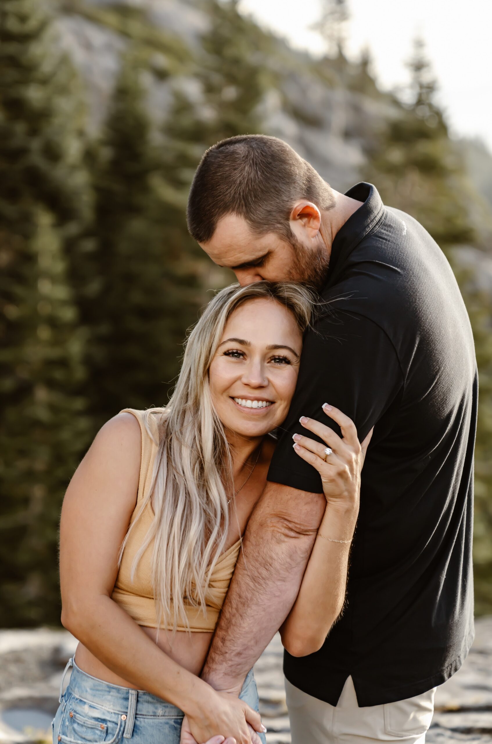 Man kisses woman on head at Emerald Bay engagement
