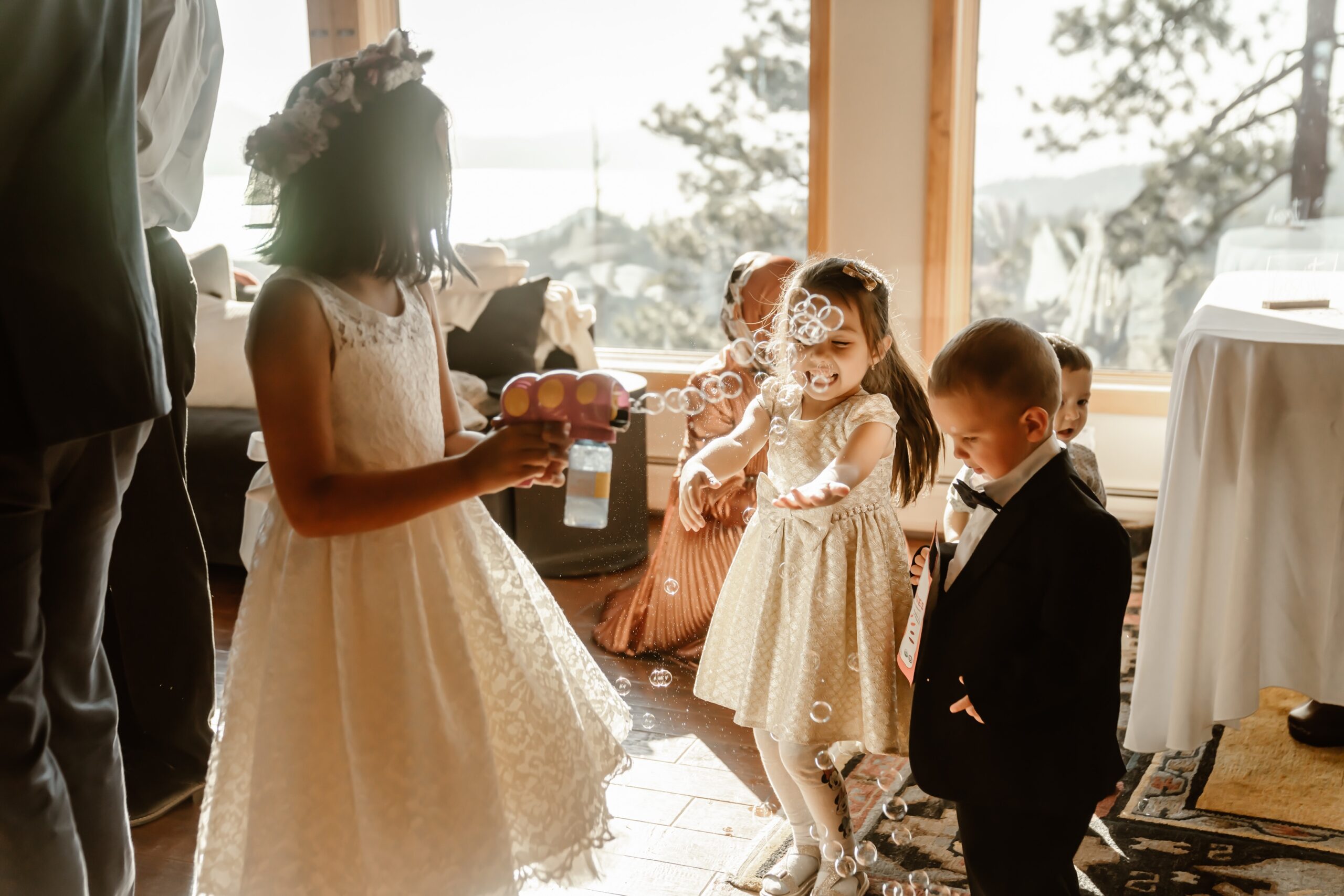 Flower girls and ring bearer play with bubbles at wedding