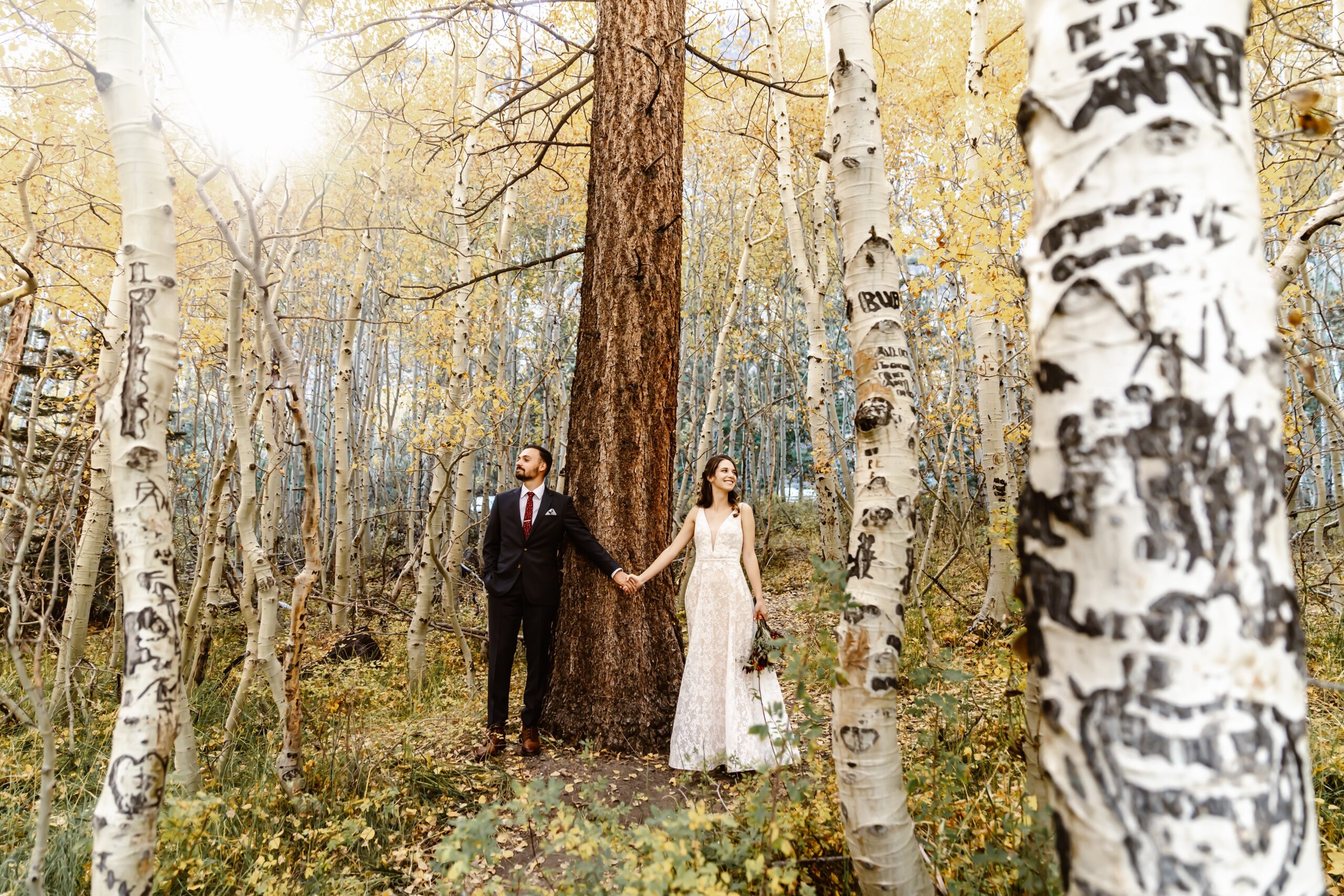 Bride and groom hold hands in the forest