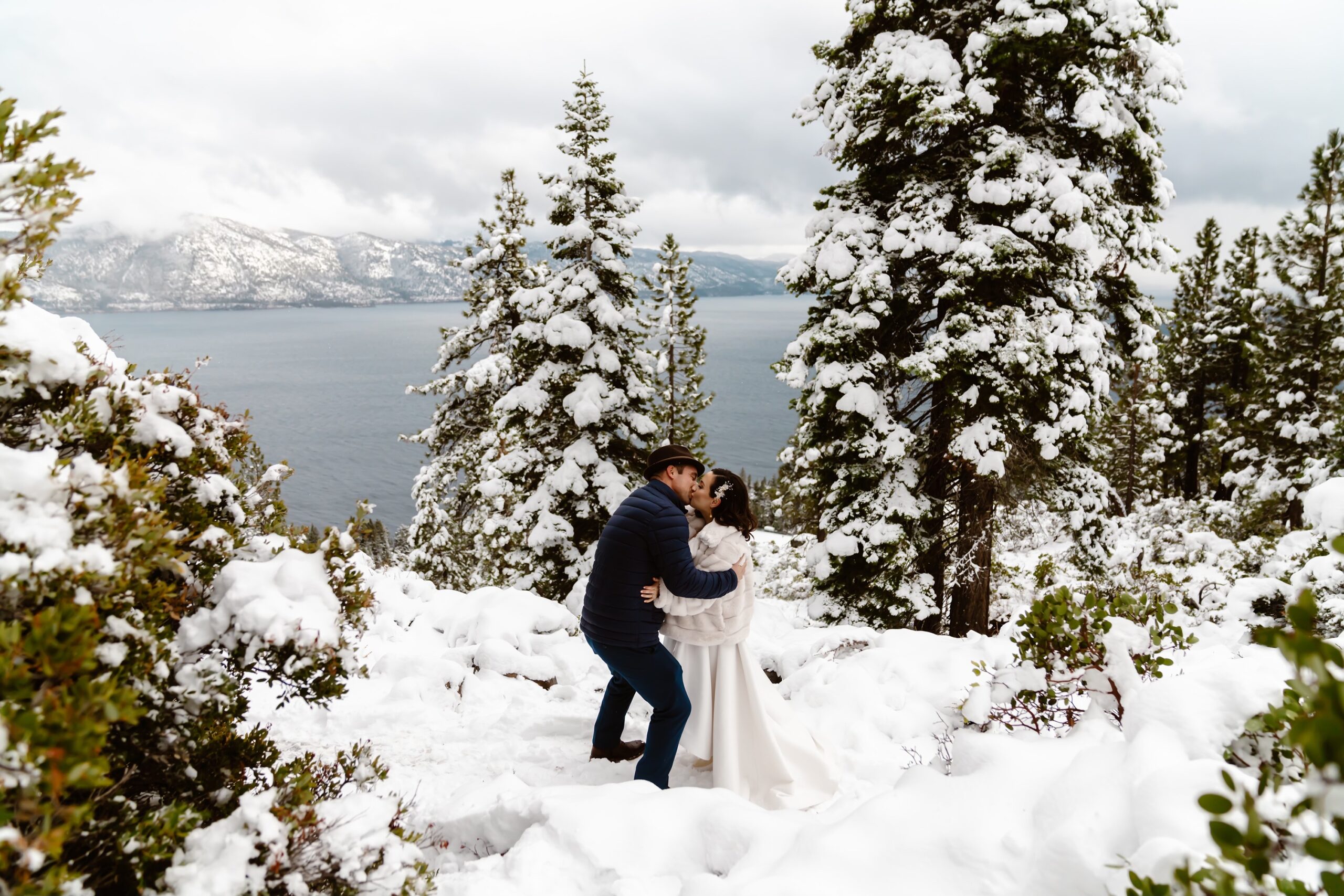 Bride and groom kiss at snowy mountain elopement