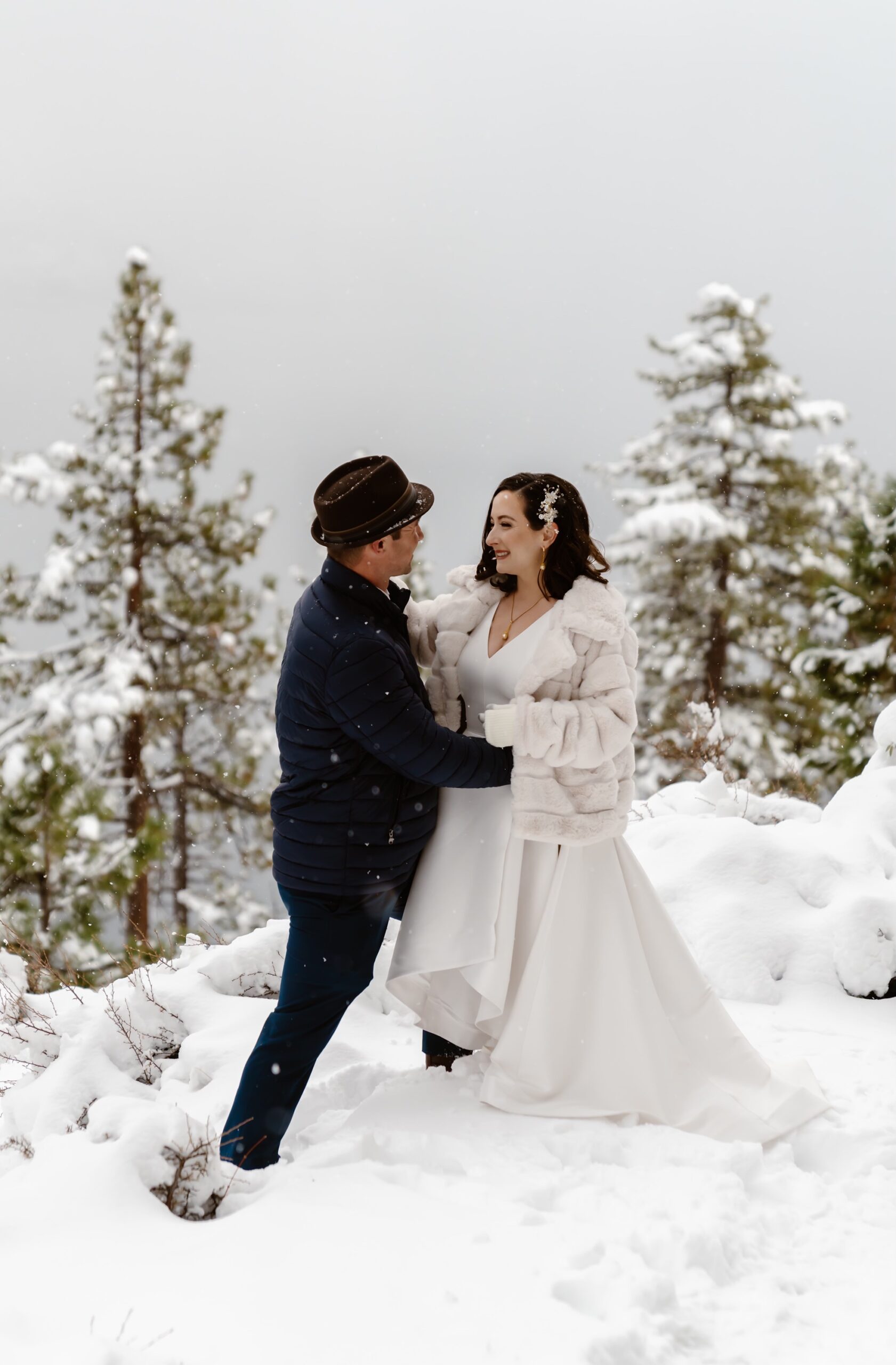 Bride and groom embrace in the snowy mountains