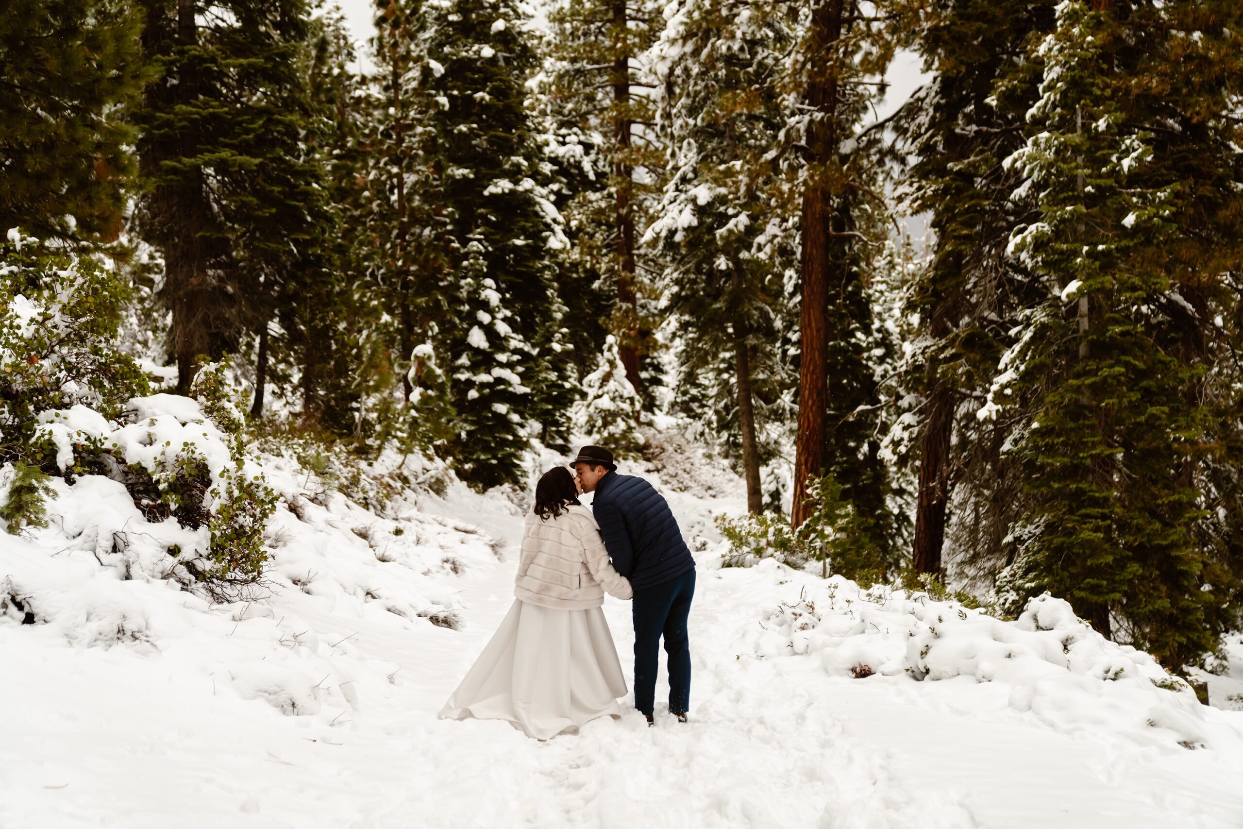 Bride and groom kiss in the snowy mountains
