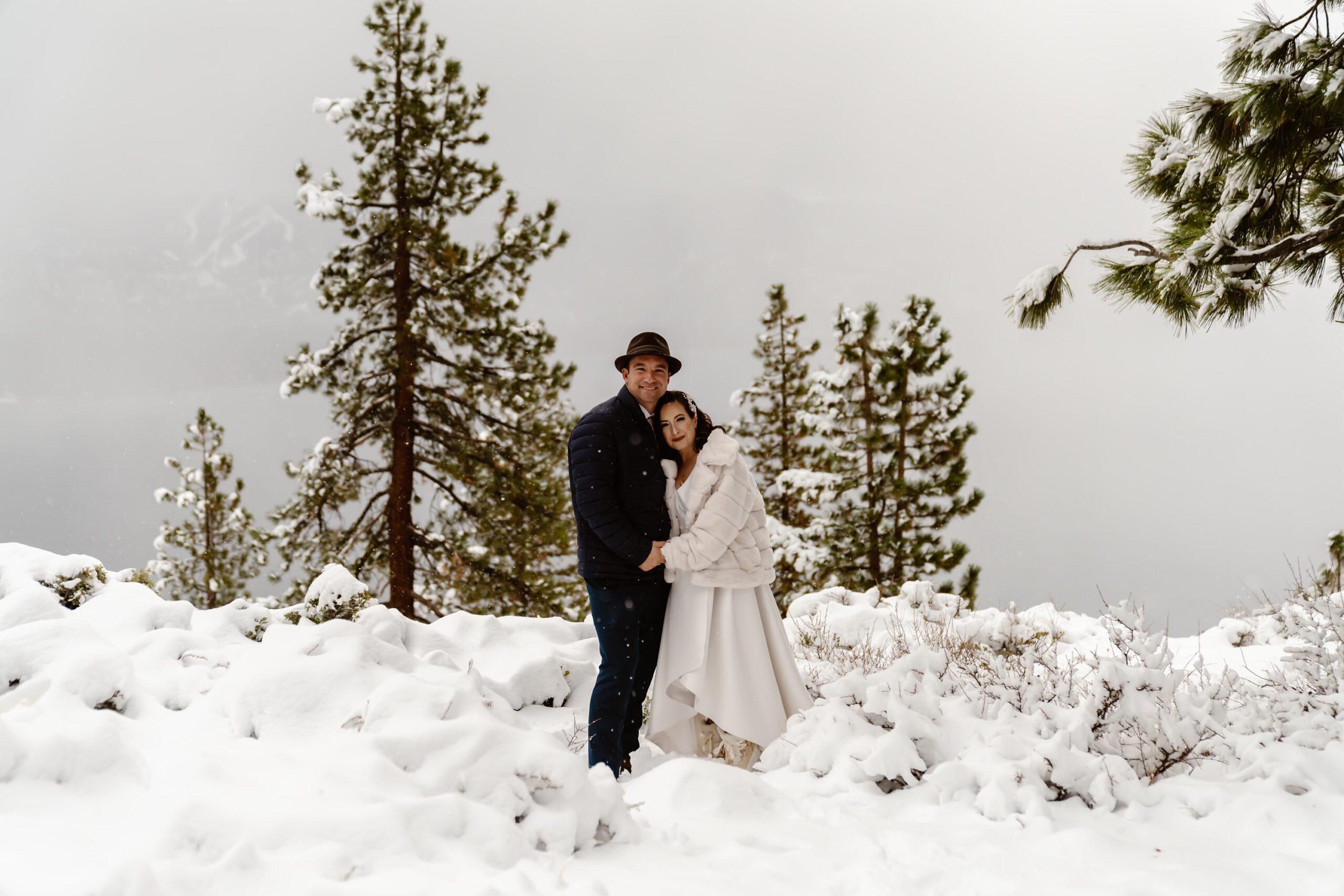 Bride and groom smile at camera during snowy mountain elopement