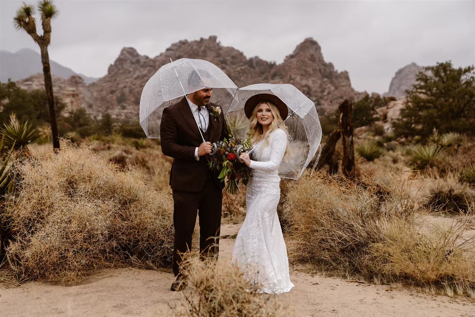 Couple poses with clear umbrellas at Joshua Tree National Park elopement
