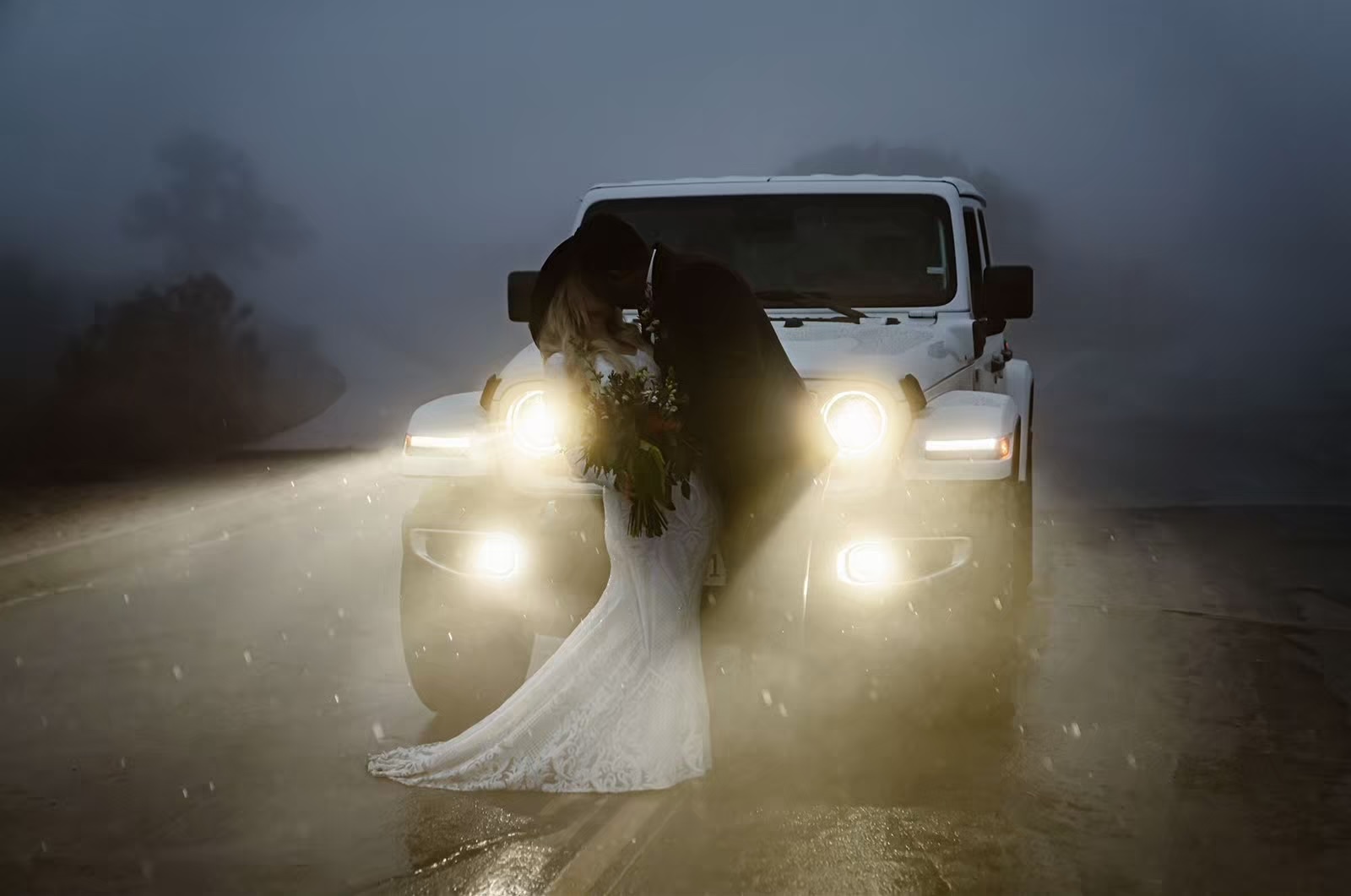 Bride and groom kiss in front of Jeep in Joshua Tree
