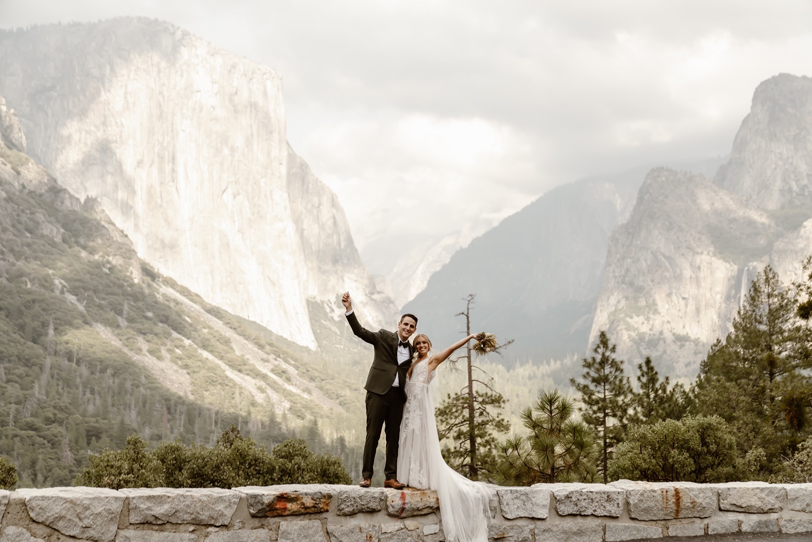 Bride and groom pose with arms in the air at their Yosemite wedding