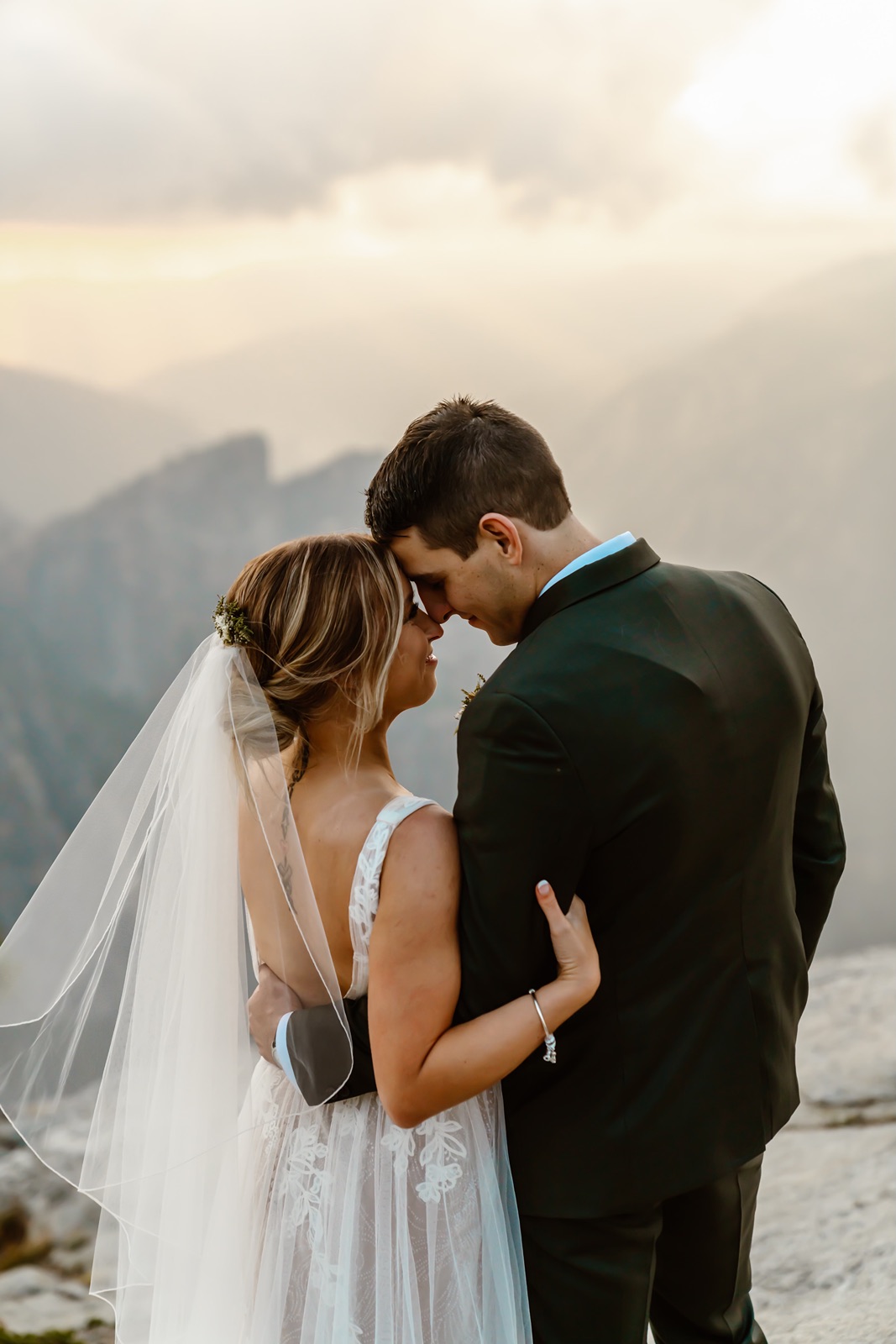 Bride and groom face away from camera with foreheads touching during Yosemite elopement
