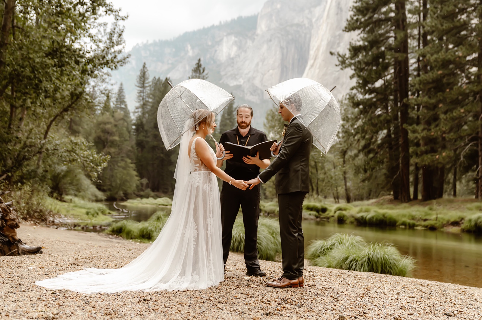 Bride and groom hold clear umbrellas during their Yosemite wedding ceremony