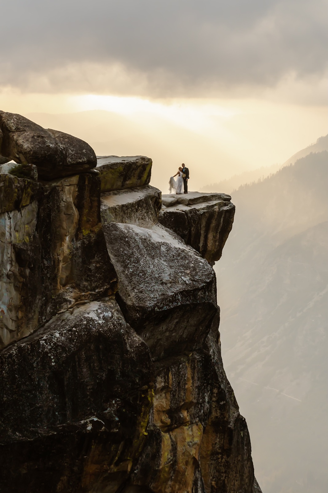 Bride and groom on a ledge at Taft Point at sunset