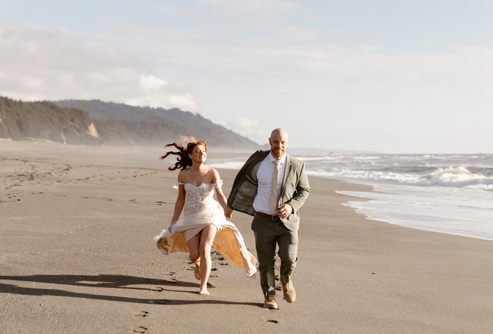 Bride and groom run on Gold Beach during elopement