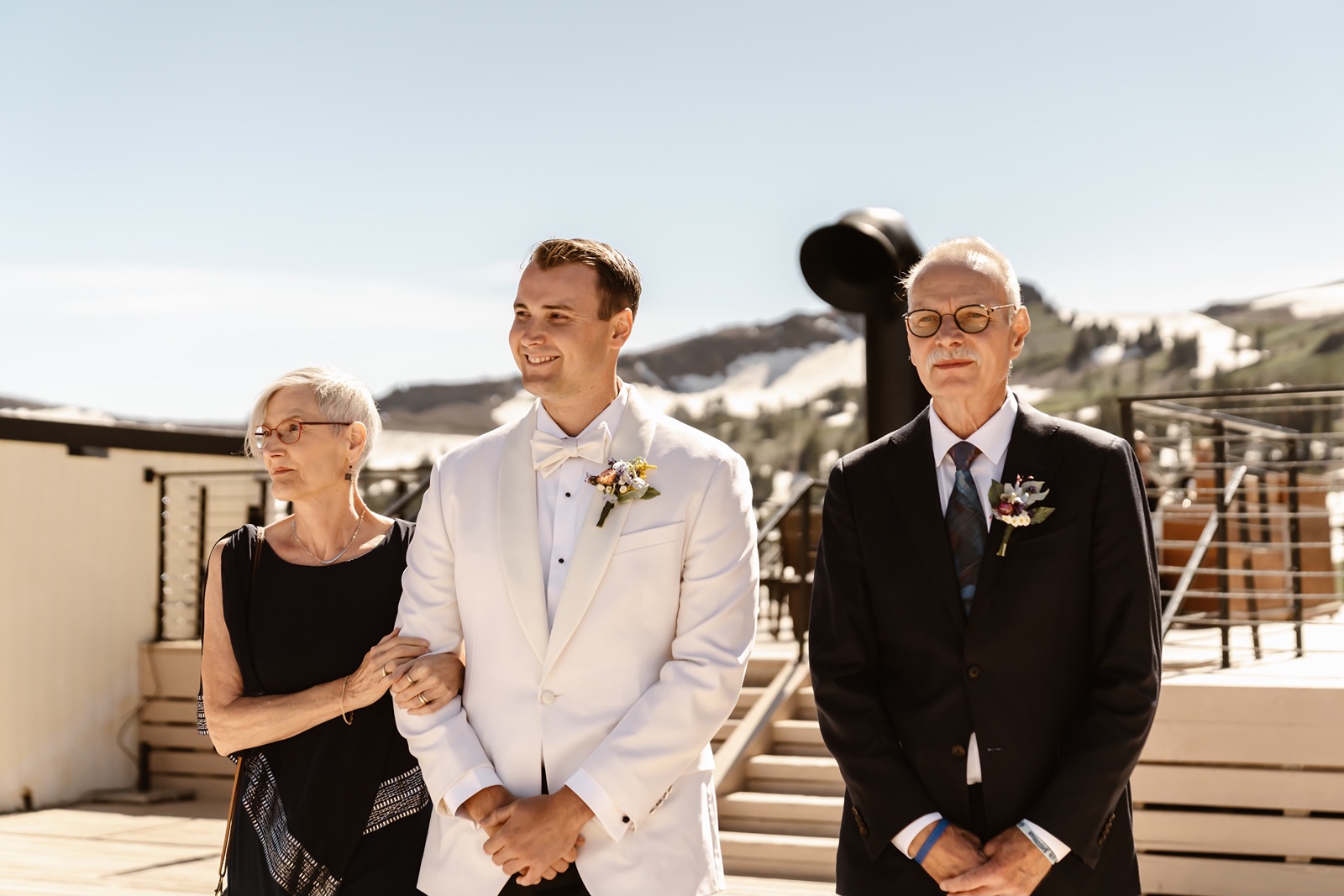 Groom walks down the aisle with his parents at the Palisades Tahoe wedding ceremony