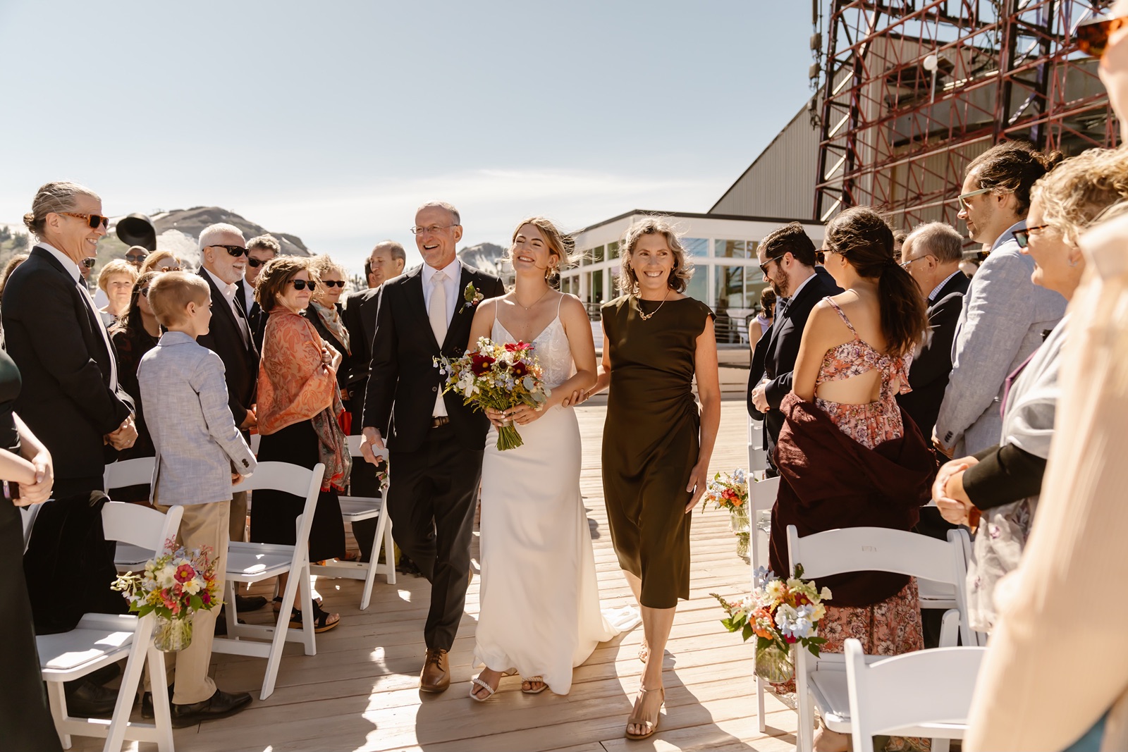 Bride walks down the aisle with her parents at the Palisades wedding ceremony