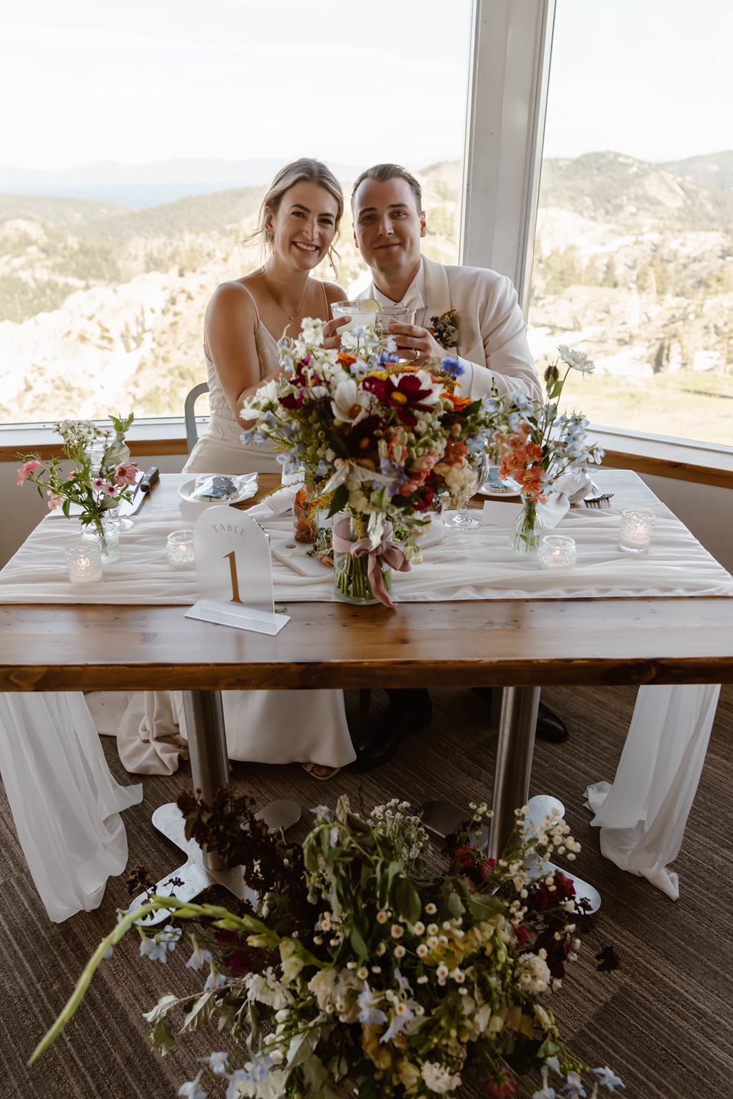 The bride and groom smile while seated at their sweetheart table