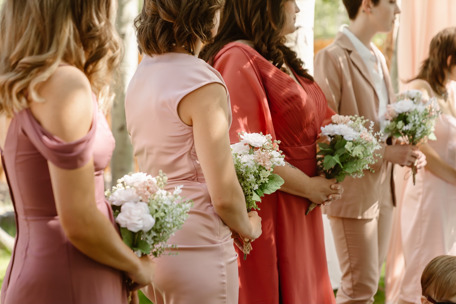 Bridesmaids hold white and light pink bouquets