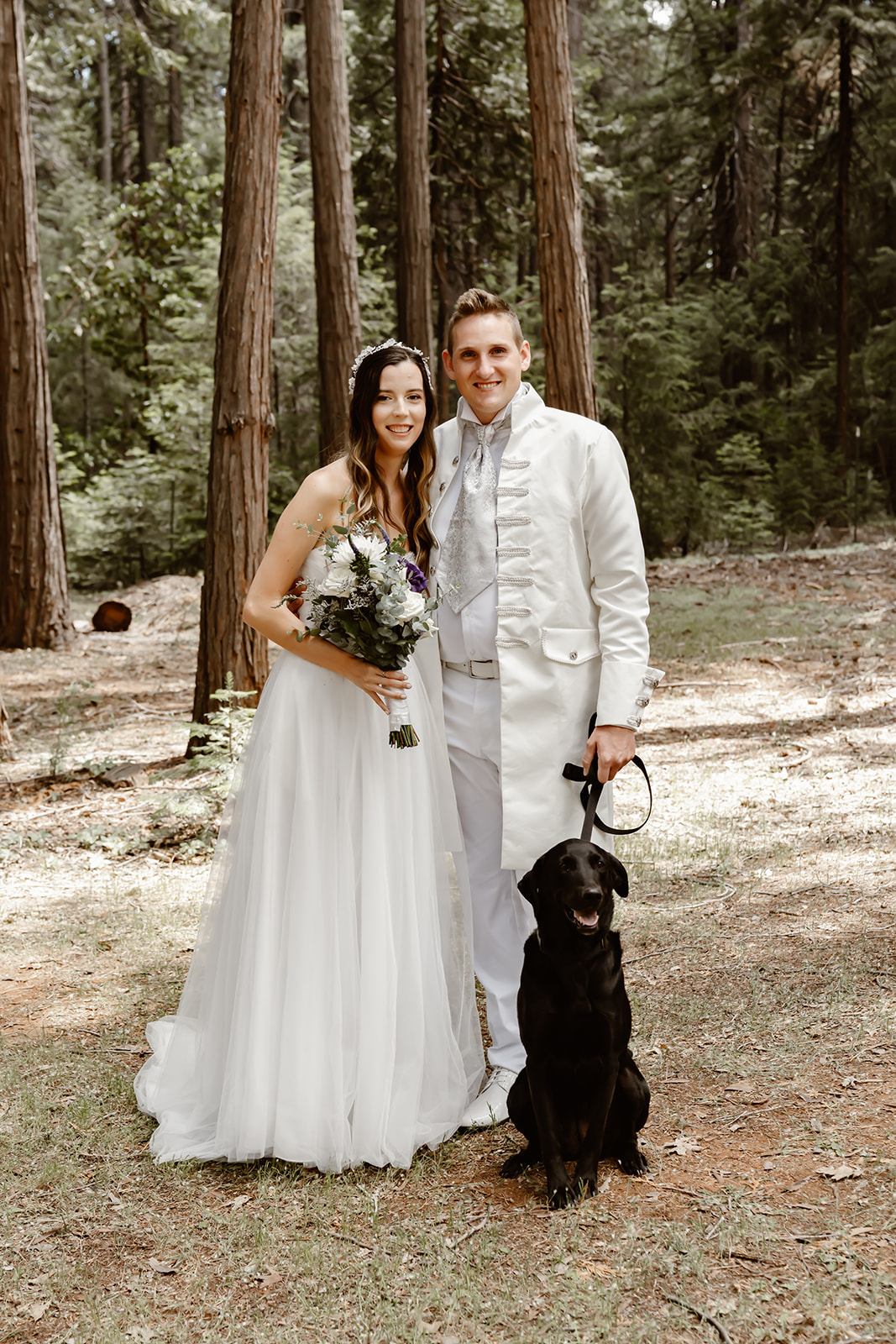 Bride and groom smile at the camera with their dog at Harmony Ridge Lodge