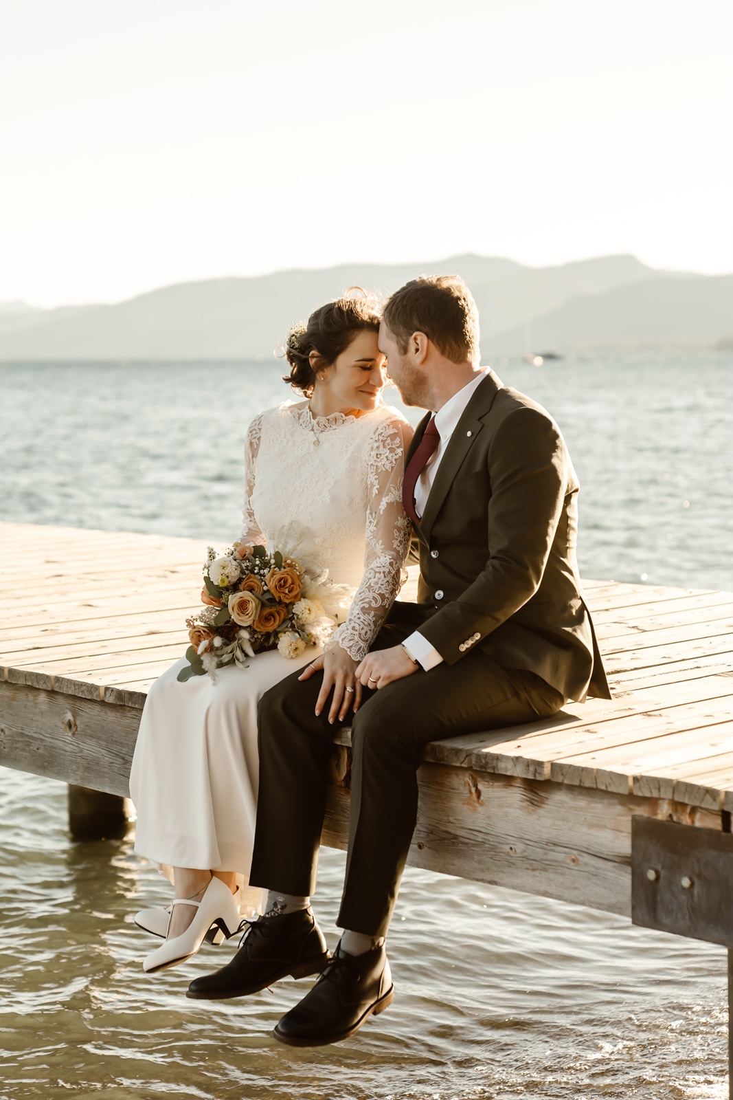 Bride and groom sit on a pier at their Skylandia Beach elopement
