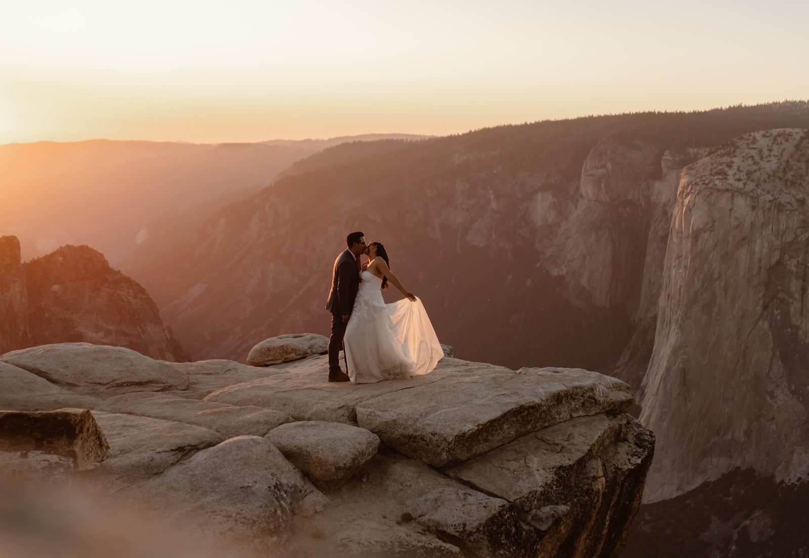 Bride and groom kiss as the sun sets behind Taft Point
