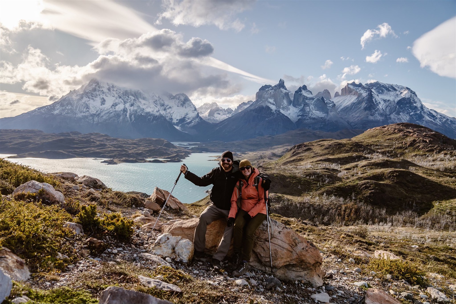 Husband and wife photographer and videographer duo pose with scenic backdrop