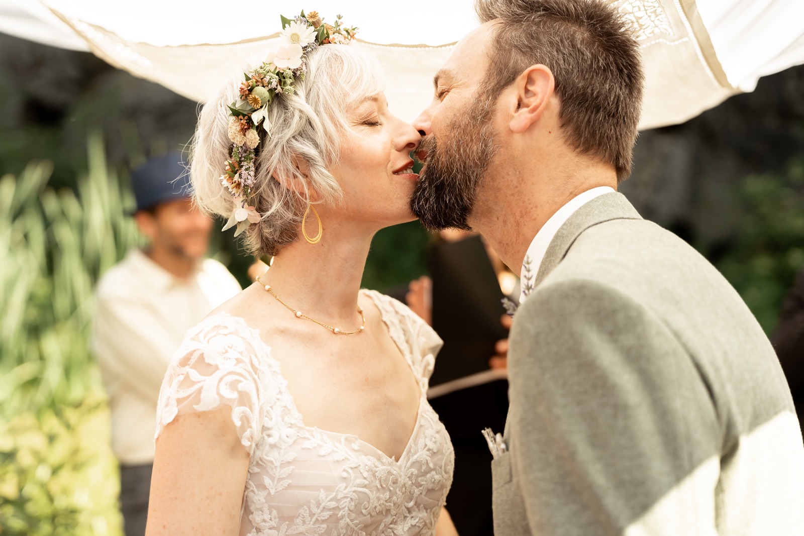 Bride and groom kiss at their outdoor wedding ceremony at Rainbow Lodge in Soda Springs