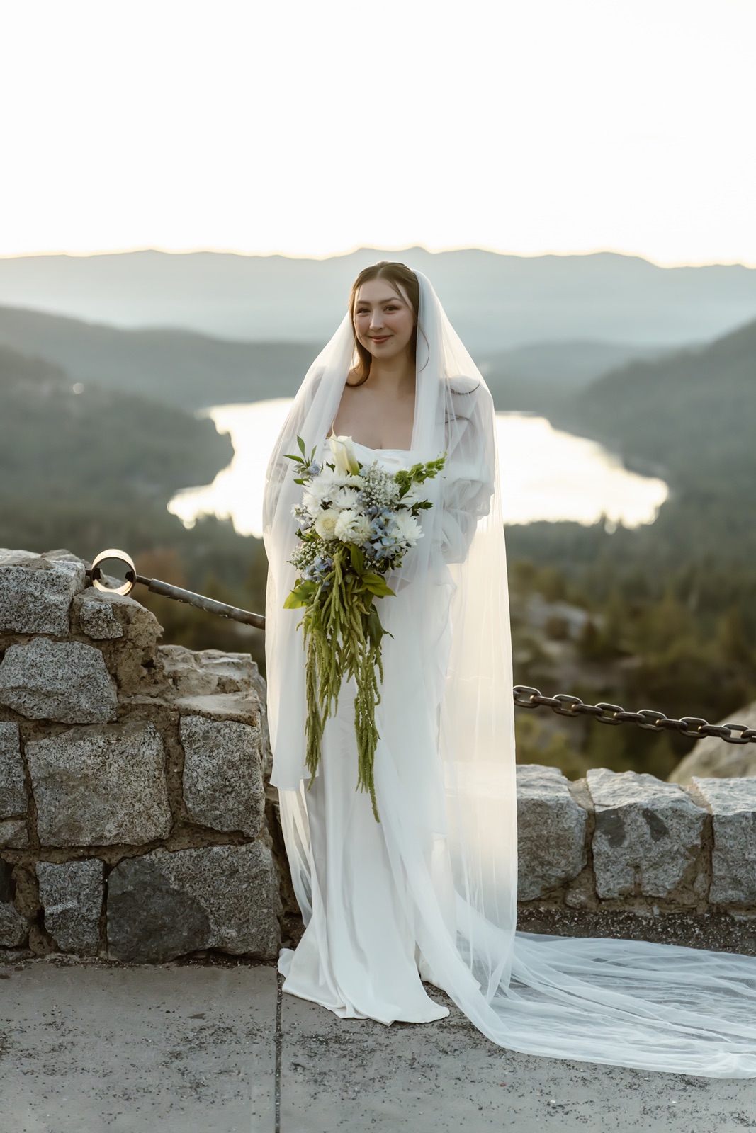 Bride holds bouquet while smiling at Donner Lake Overlook