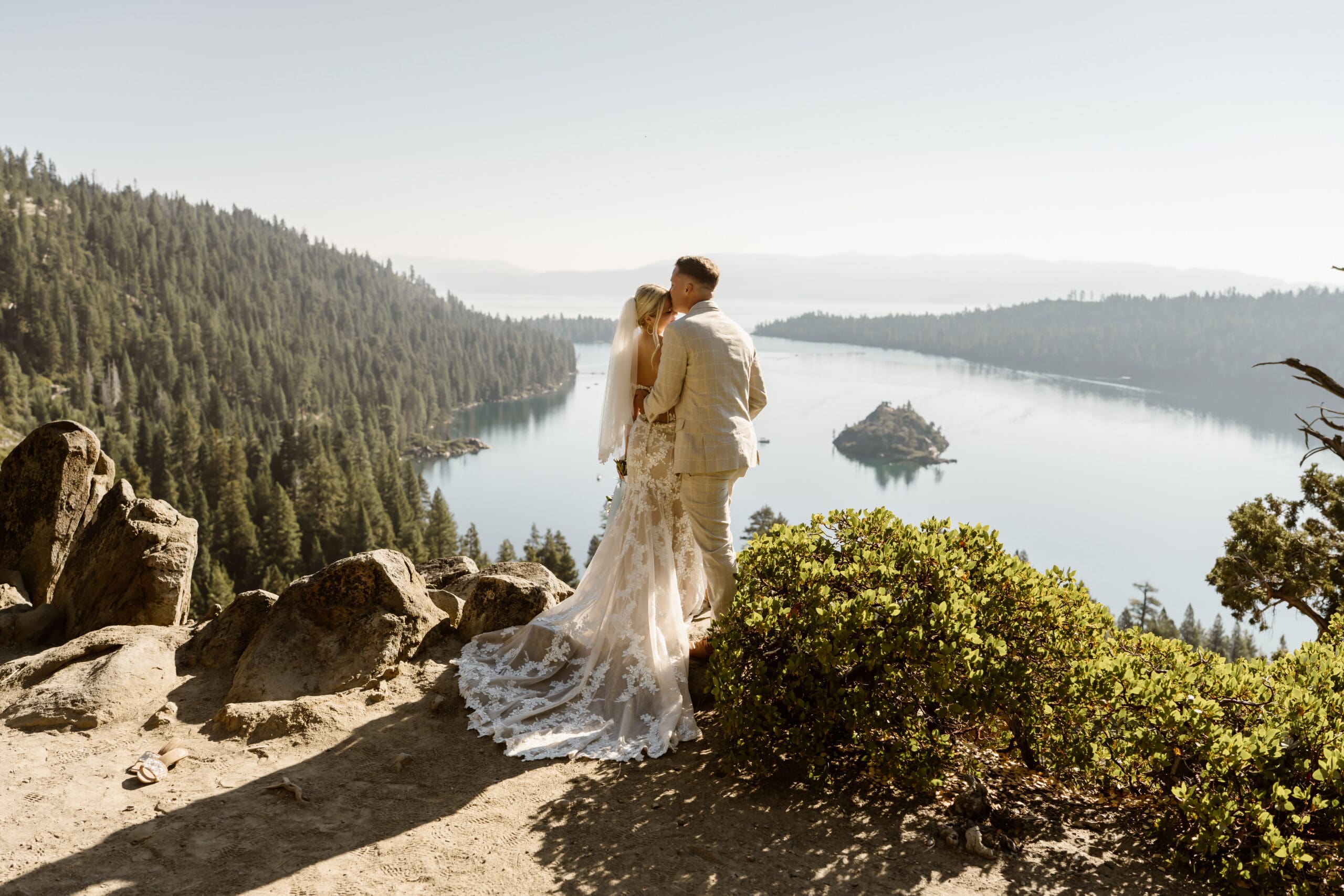 Bride and groom embracing at an Emerald Bay overlook during their Lake Tahoe elopement, with Fannette Island and the lake behind them.