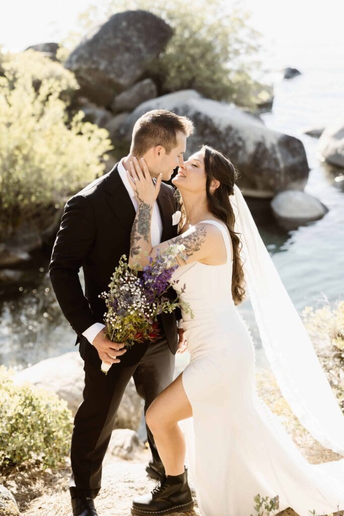 Lake Tahoe Elopement Guide 1 Newlywed couple embracing beside the rocky Lake Tahoe shoreline during their elopement