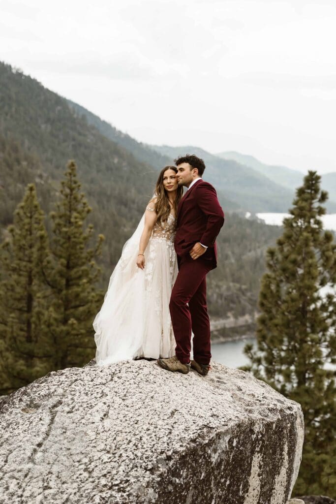 Lake Tahoe Elopement Guide 3 Newlywed couple standing on a granite boulder overlooking Lake Tahoe and the surrounding mountains