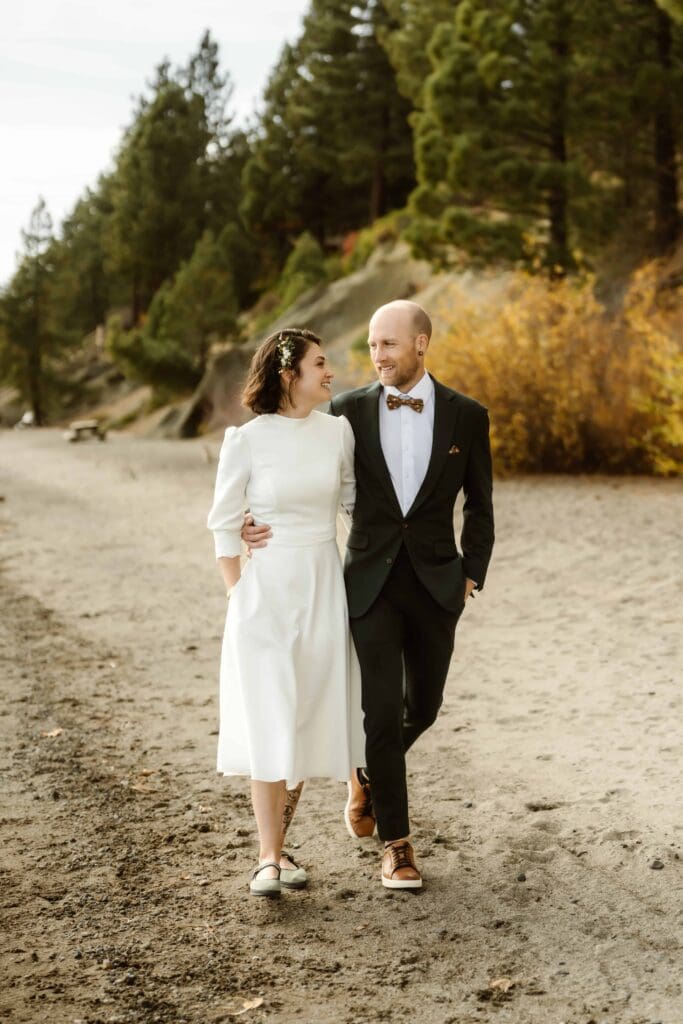 Couple walking along the Lake Tahoe shoreline during their fall elopement