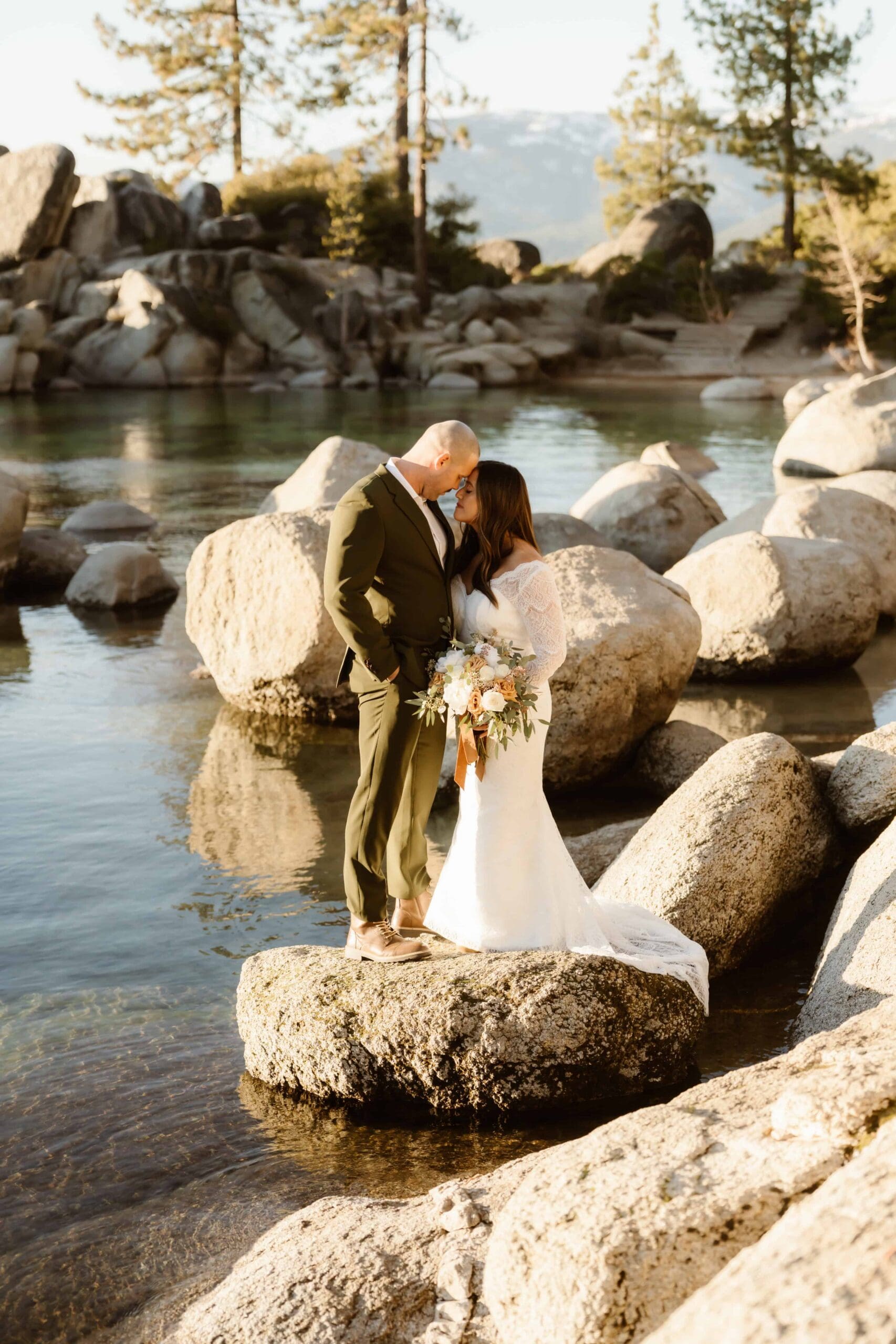 Bride and groom standing on granite rocks at Sand Harbor during their Lake Tahoe elopement, surrounded by clear water and boulders.