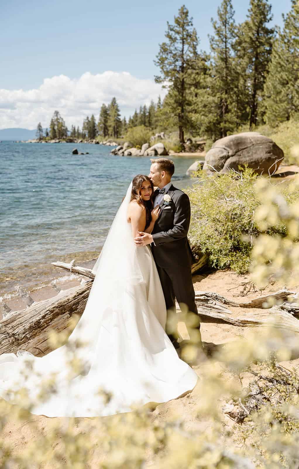 Bride and groom exchanging vows along the Lake Tahoe shoreline at Zephyr Cove, surrounded by pine trees and granite boulders.
