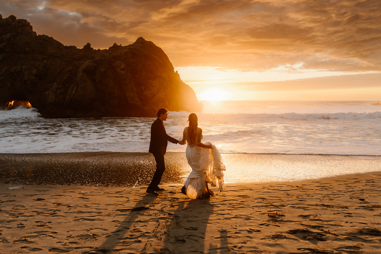 Bride and groom hold hands at sunset in Big Sur, California