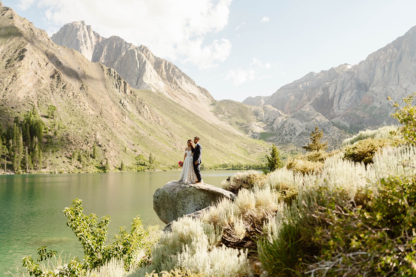 Couple on a rock over a river at their destination elopement